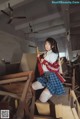 A woman in a school uniform sitting on top of a wooden box.