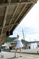 A woman in a white dress is standing on a train platform.