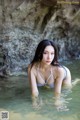 A woman in a bikini laying in the water.