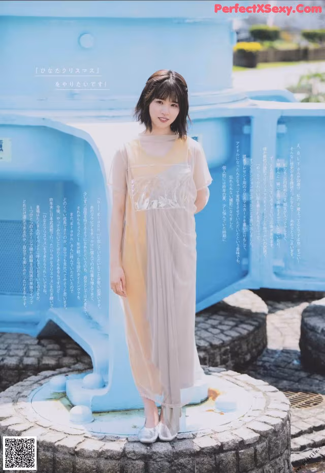 A woman standing in front of a blue trash can.