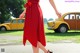 A woman in a red dress is walking down the street.