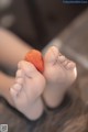 A person holding a strawberry in their bare feet.