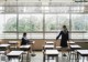 A woman standing in front of a classroom full of desks.