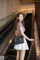 A woman standing on an escalator holding a black bag.