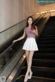 A woman standing on an escalator holding a cell phone.